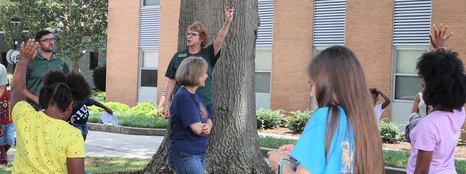 Dr. Lynn Hoekstra stands before a tree as she teaches about nature to students of the Carolina School for Inquiry. 